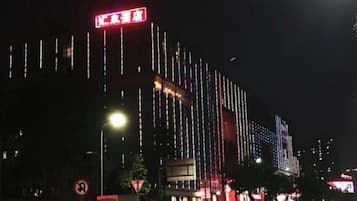 A building with vertical light strips and a red sign at the top.