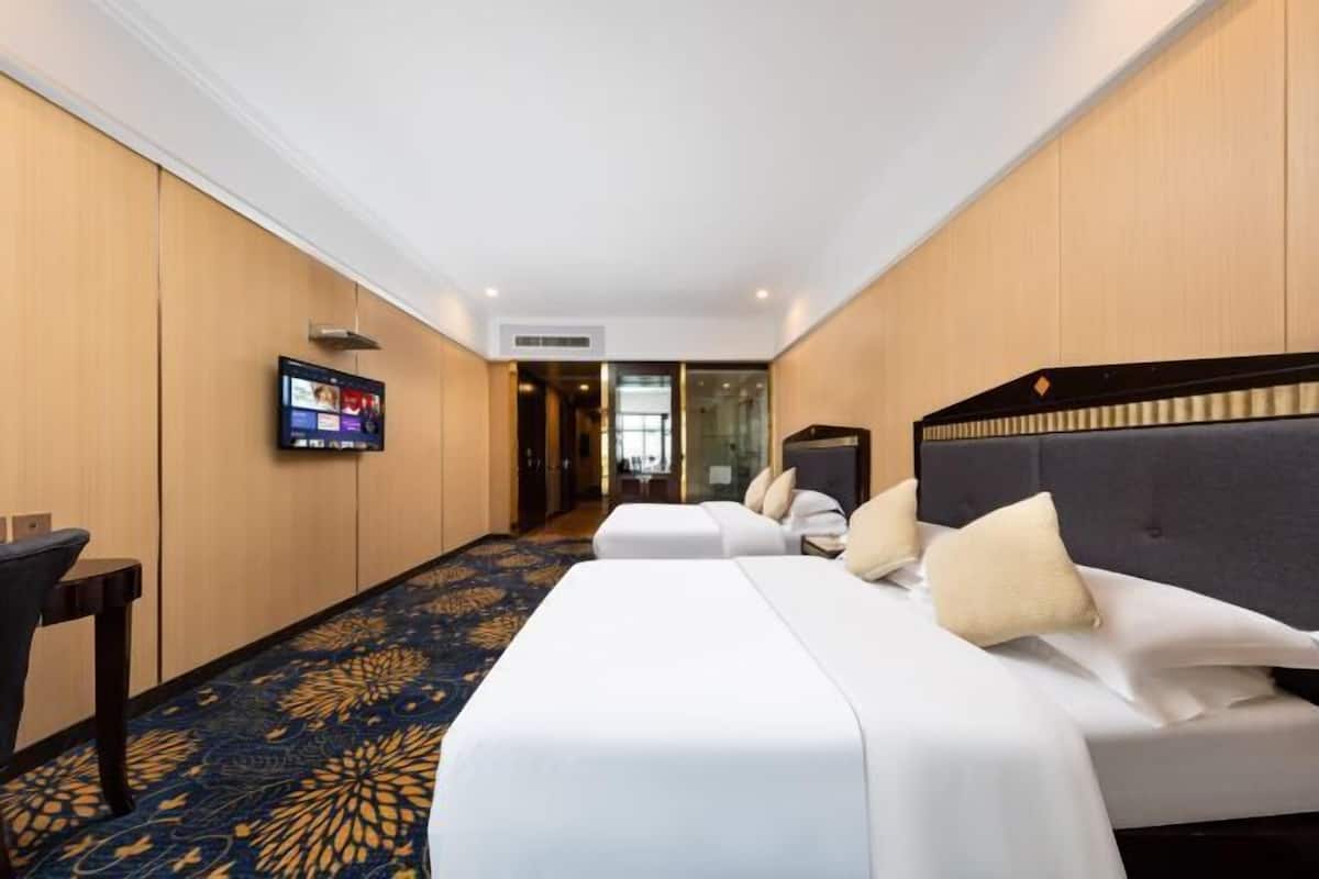 Een hotelkamer met twee bedden, een televisie en een vloerbedekking.