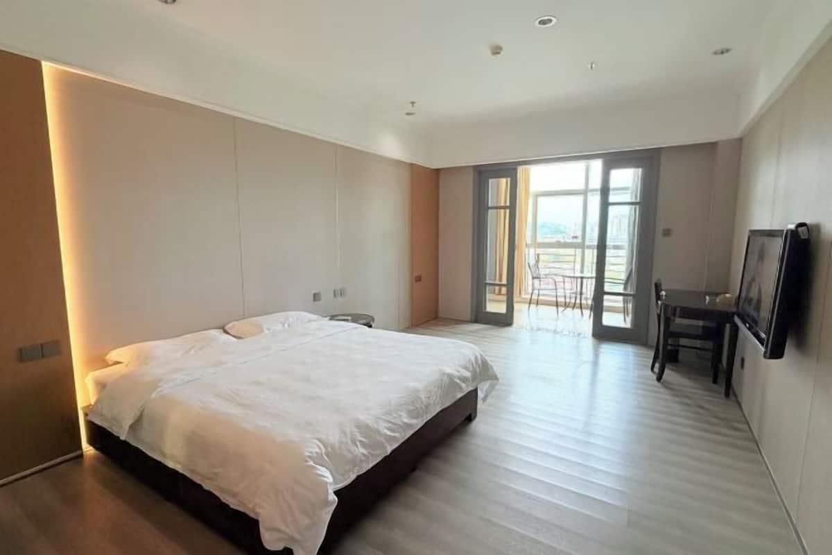 Een moderne slaapkamer met een groot bed, een bureau en een televisie.
