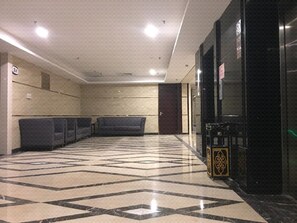 A lobby with a patterned floor, seating area, and a reception desk.
