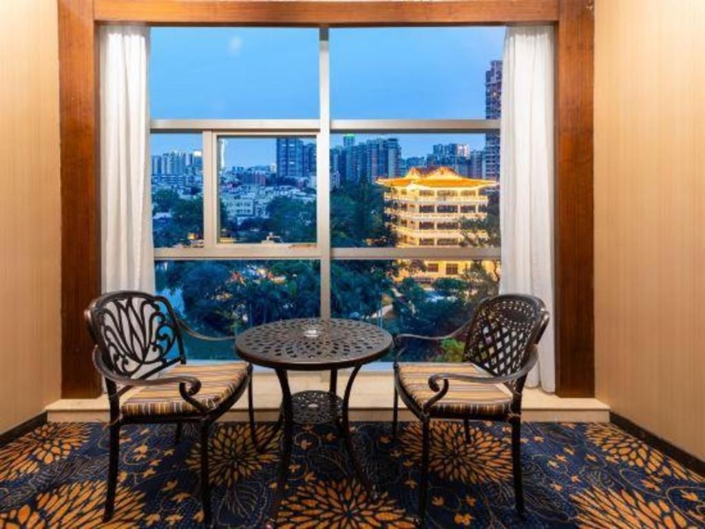 A room with a large window, two chairs, a small table, and a patterned carpet.