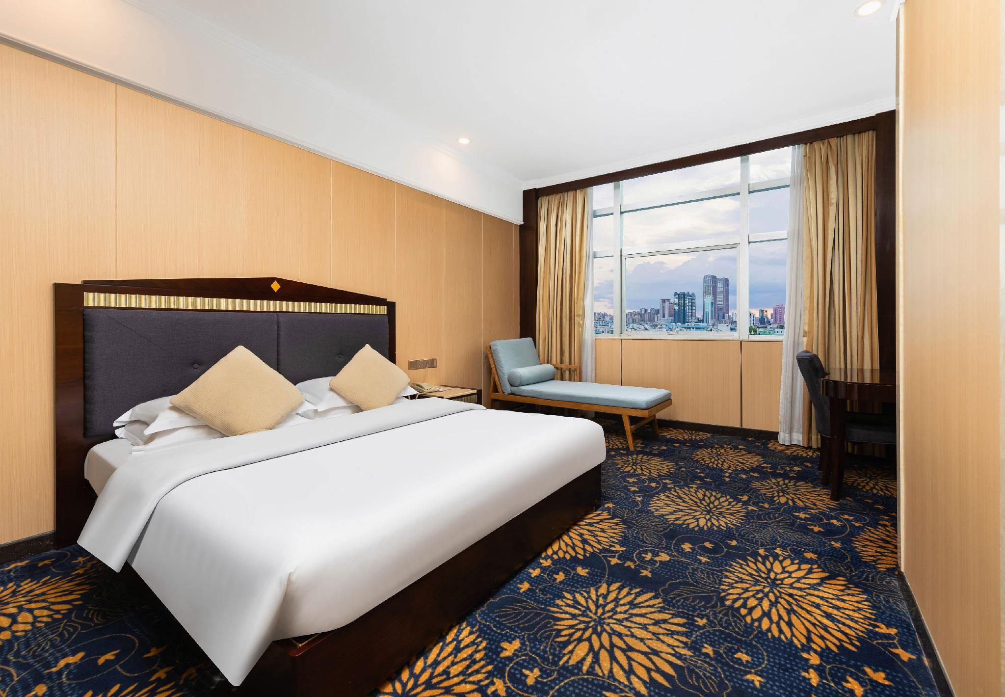 Une chambre d’hôtel avec un grand lit, une chaise, un bureau et une vue sur le paysage urbain.