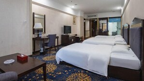 Une chambre d’hôtel avec deux lits, un bureau avec une chaise, une télévision et une salle de bain visible à travers une porte ouverte.