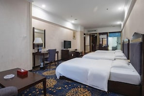 A hotel room with two beds, a desk with a chair, a television, and a bathroom visible through an open door. - Huiquan Hotel (Zhongshan)