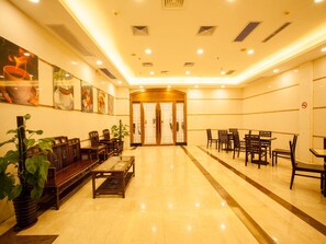 A hotel lobby with a reception desk, seating area, and a glass partition.