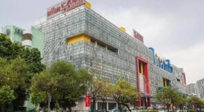 A multi-story building with a glass facade, surrounded by trees and other buildings. - Huiquan Hotel (Zhongshan)