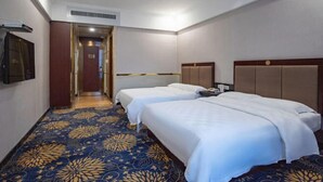 Une chambre d’hôtel avec deux lits, une moquette à motifs, une tête de lit en bois et une porte donnant sur une autre pièce.