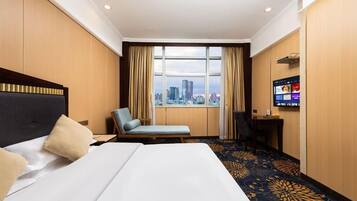 Una habitación de hotel con una cama, una silla, un escritorio y un televisor.