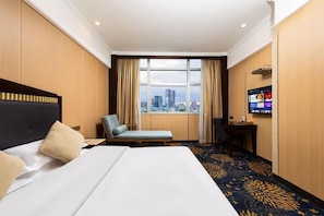 Een hotelkamer met een bed, een stoel, een bureau en een televisie.