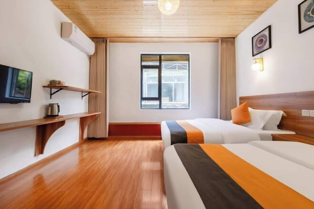 A hotel room with a wooden ceiling, a large window, a bed with striped bedding, a bedside table, and a flat-screen TV.