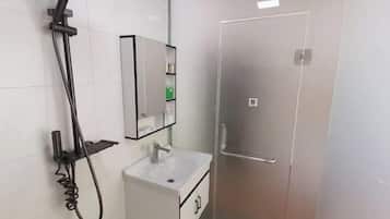 Ein Badezimmer mit Dusche, Waschbecken und Spiegel.