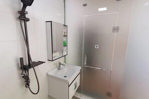 A bathroom with a shower, sink, and mirror. - Miyi lnn (Xiaojin)