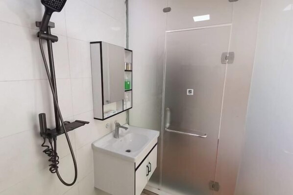 A bathroom with a shower, sink, and mirror. - Miyi lnn (Xiaojin)