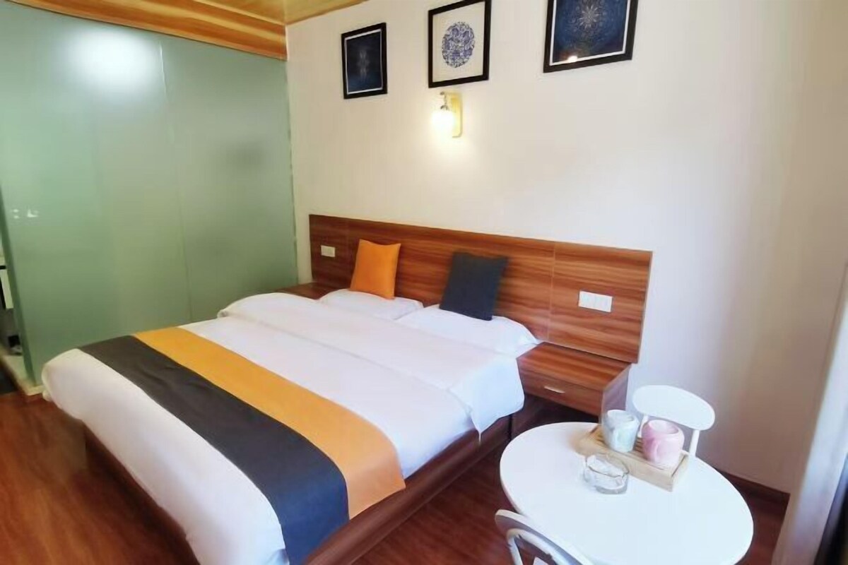 A hotel room with a wooden headboard bed, white bedding, and a small round table with a cup and saucer.
