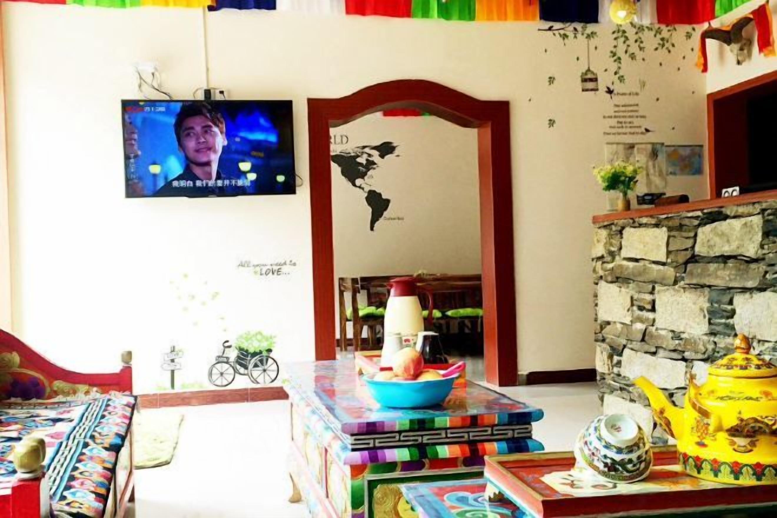 Ein Zimmer mit einem an der Wand befestigten Fernseher, einer Steinsäule, einem Tisch mit einem Teekessel und einer Fahrraddekoration.