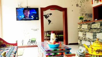 Ein Zimmer mit einem an der Wand befestigten Fernseher, einer Steinsäule, einem Tisch mit einem Teekessel und einer Fahrraddekoration.