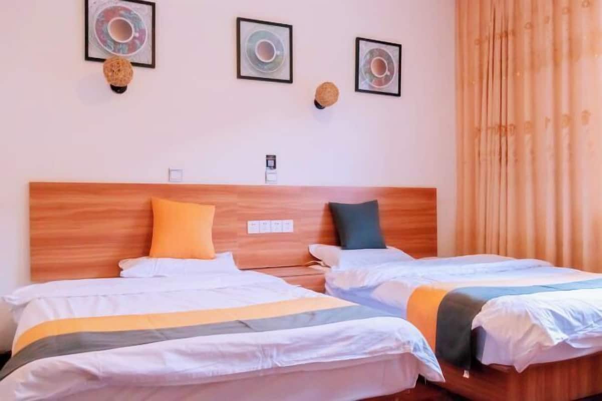 A hotel room with two beds, a wooden headboard, and a wall-mounted light fixture.