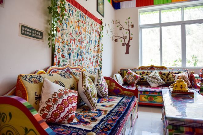 A traditional room with a sofa set, a patterned wall hanging, and a window with a view.