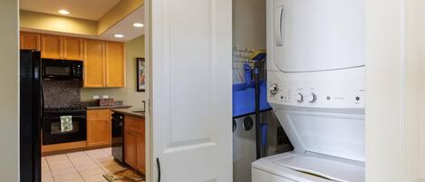 A kitchen with wooden cabinets, a black refrigerator, a microwave, and a stove.