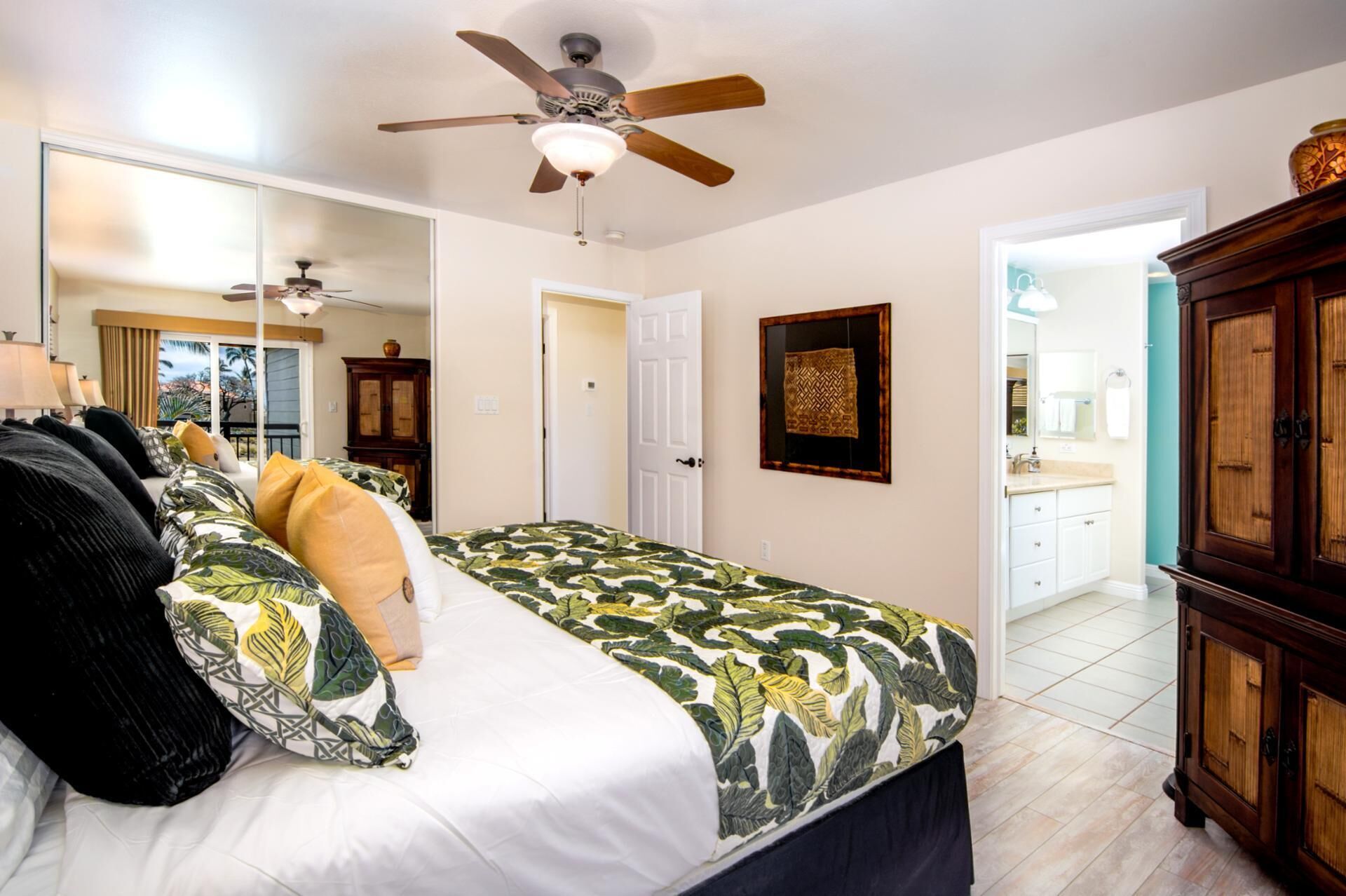 Ein Schlafzimmer mit einem Bett, einem Deckenventilator, einem Kleiderschrank und einem durch eine offene Tür erreichbaren Badezimmer.