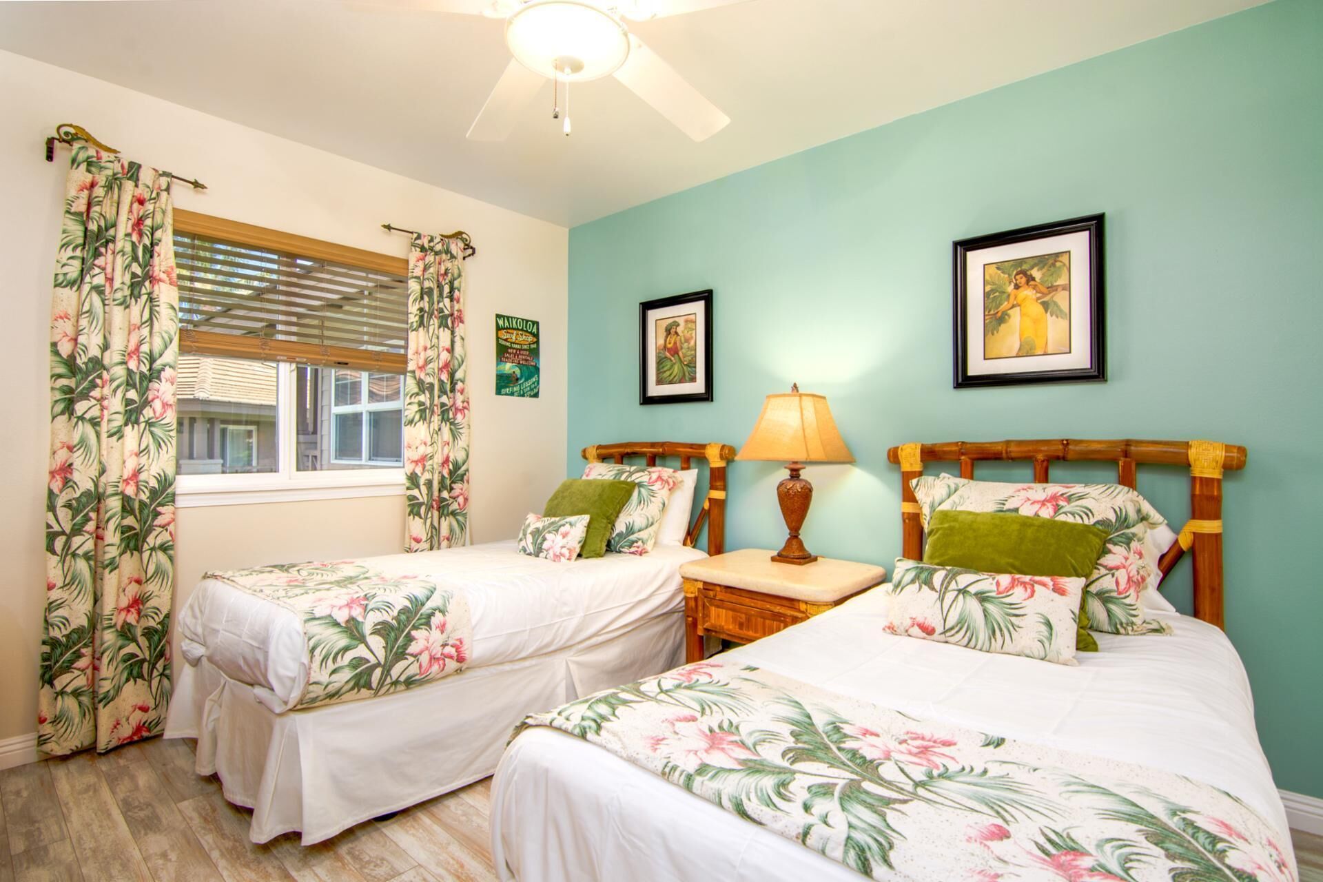 A room with two single beds, a wooden headboard, a nightstand with a lamp, and a window with blinds.