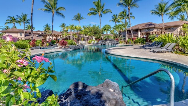 A swimming pool surrounded by palm trees and lounge chairs, with a clear blue sky above. - Waikoloa Colony Villas Resort by KBM (Waikoloa)