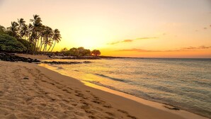 A beach with a clear view of the ocean and palm trees. - Waikoloa Colony Villas Resort by KBM (Waikoloa)