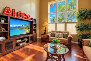 Una sala de estar con televisor, mueble de madera para entretenimiento, sofá y una mesa de centro de vidrio.