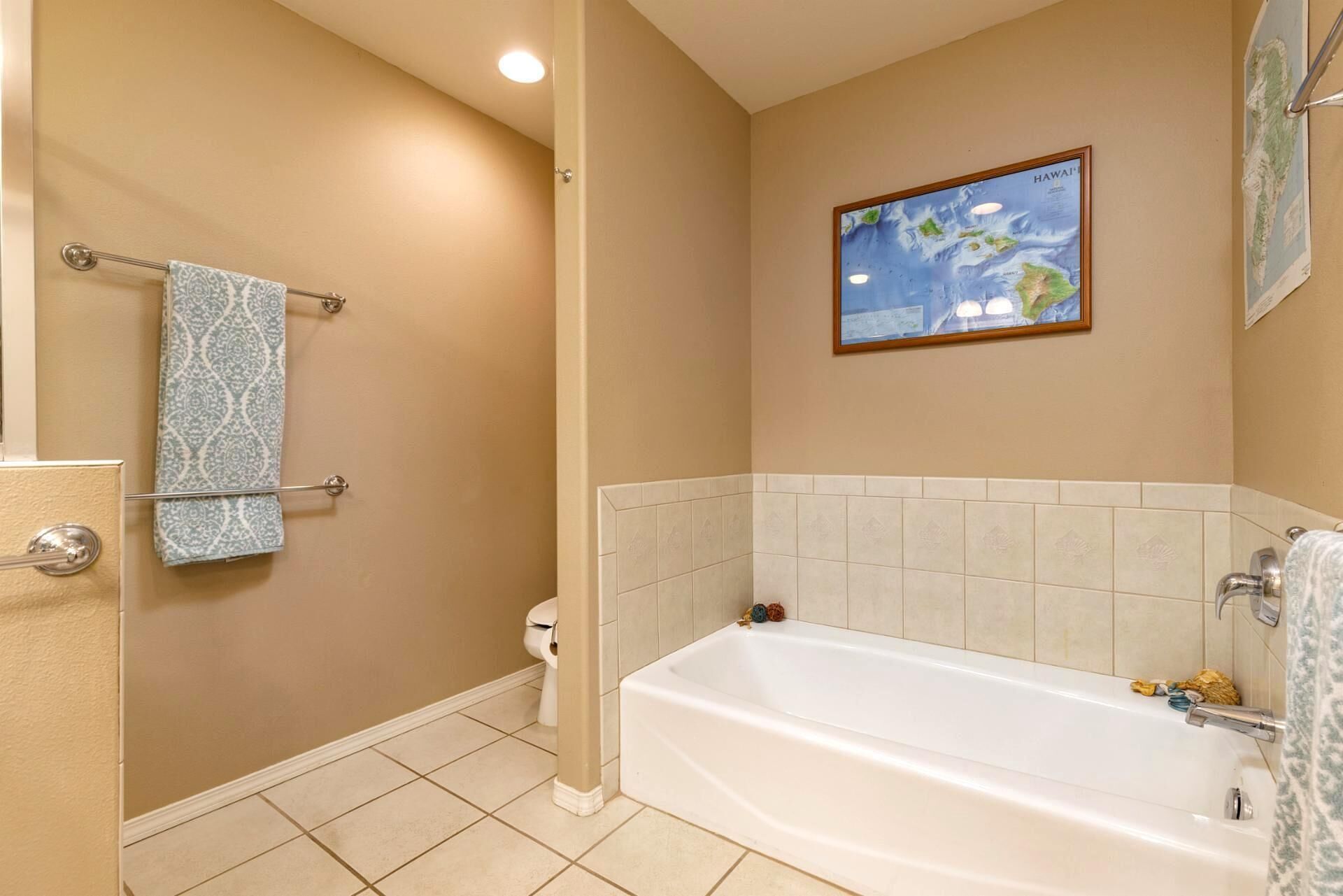 A bathroom with a bathtub, a toilet, and a towel rack with patterned towels.