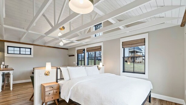 Ein Schlafzimmer mit einem großen Bett, Holzboden und Blick ins Freie.