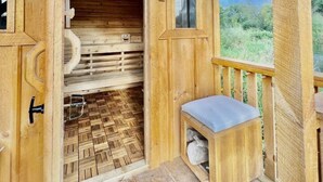 Eine Holzhütte mit einer Holzbank und einem kleinen Tisch, einem Holzboden und einem Fenster mit Blick auf Grünflächen.