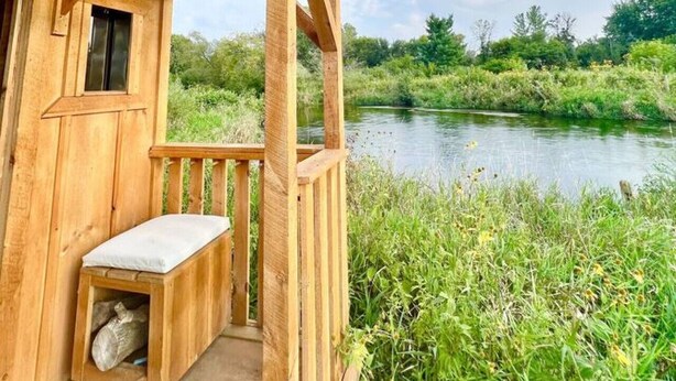 Une cabane en bois avec une véranda donnant sur une rivière.