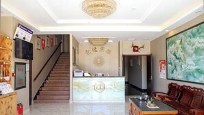 A hotel lobby with a reception desk, a staircase, a seating area, and a large painting on the wall. - Yida Hotel (Changbai Mountain West Slope Tourist Transfer Center) (Fusong)
