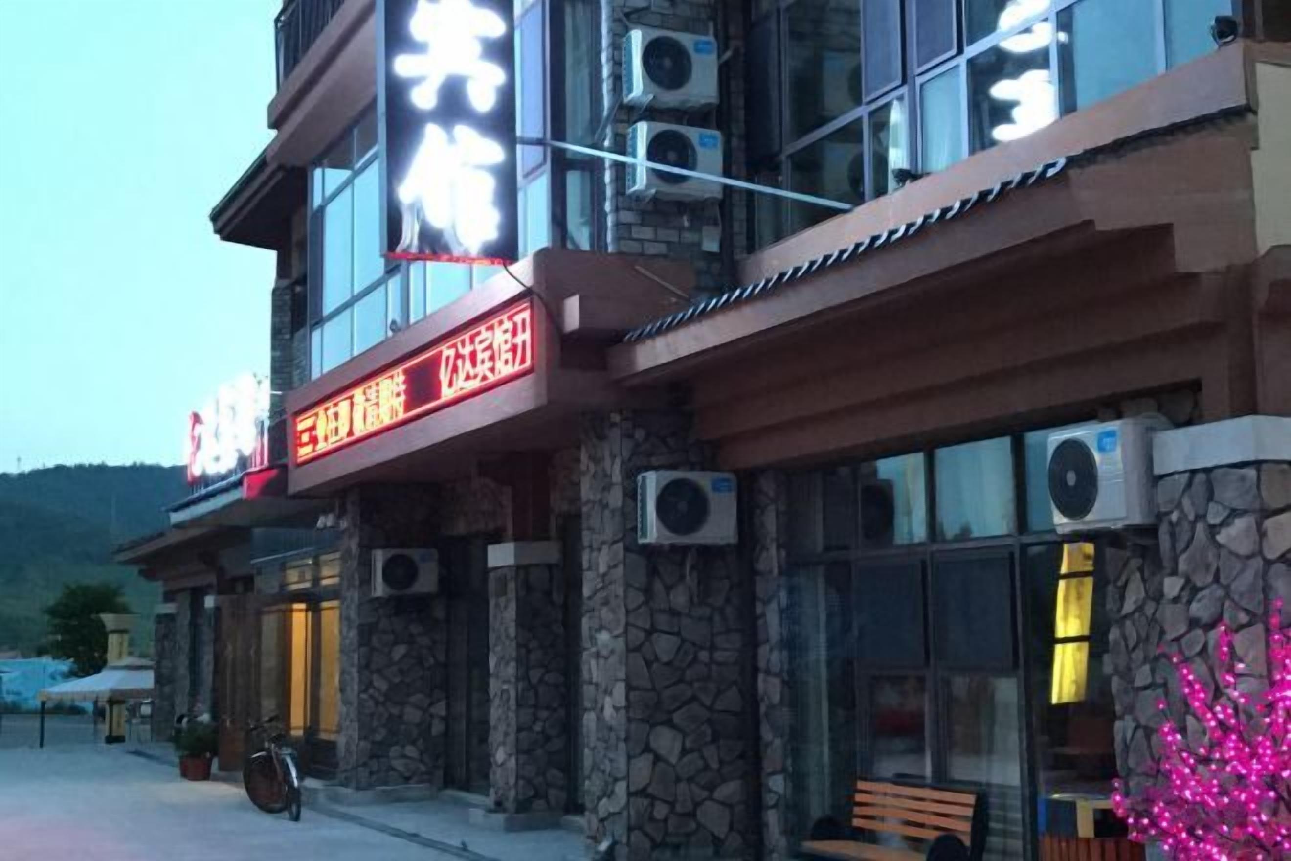 A building with a stone facade, large windows, and a sign with illuminated text.