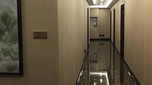 A long, narrow hallway with a marble floor, a framed artwork on the left wall, and a light switch on the wall. - Yida Hotel (Changbai Mountain West Slope Tourist Transfer Center) (Fusong)