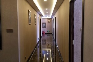 Un pasillo de hotel con cuadros en las paredes, suelo pulido y una puerta al final.