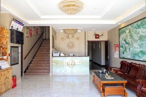 A hotel lobby with a reception desk, a staircase, a dining area with a table and chairs, and a large floral painting on the wall. - Yida Hotel (Changbai Mountain West Slope Tourist Transfer Center) (Fusong)