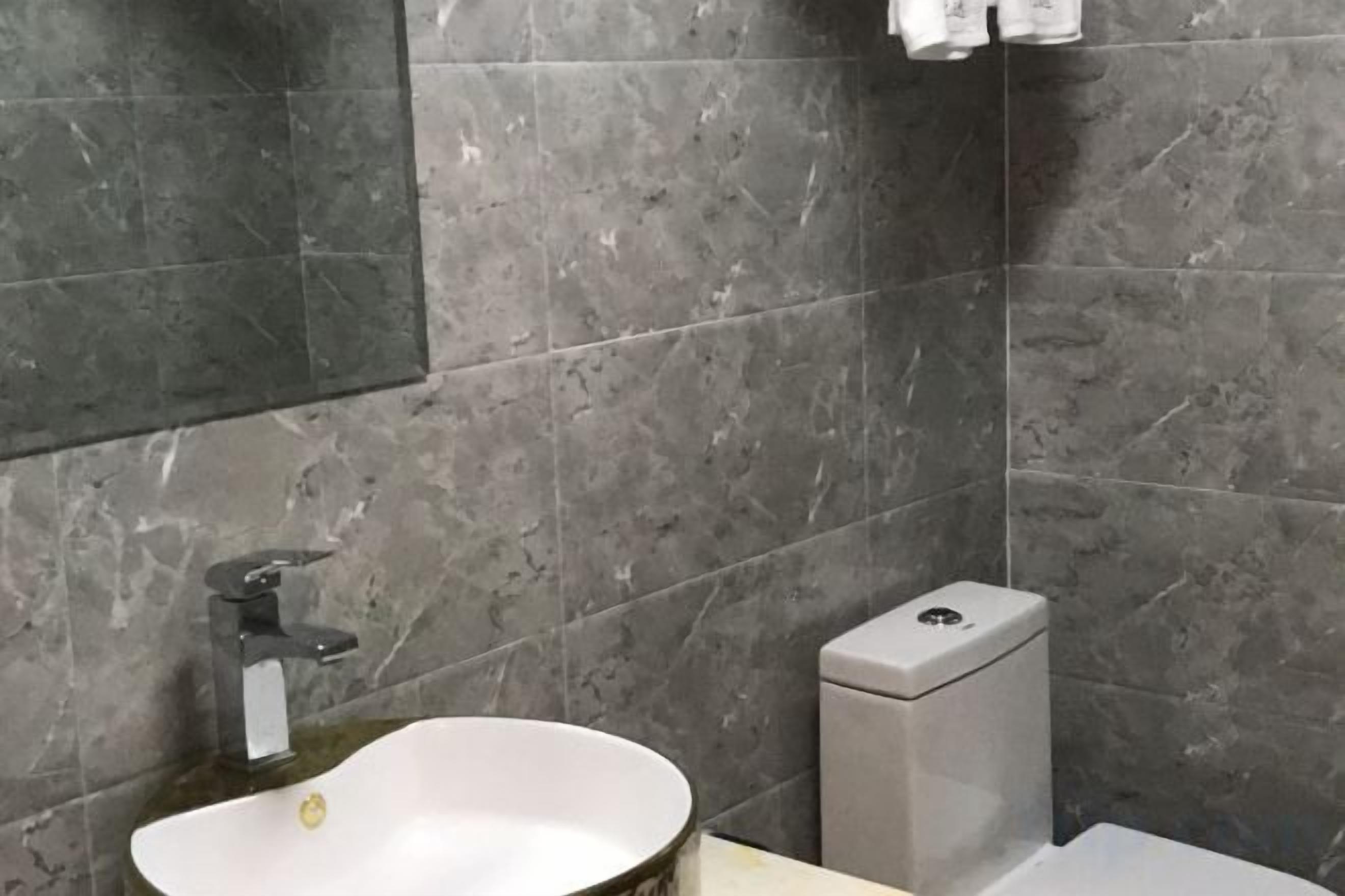 A bathroom with a white sink, a mirror, and a toilet.