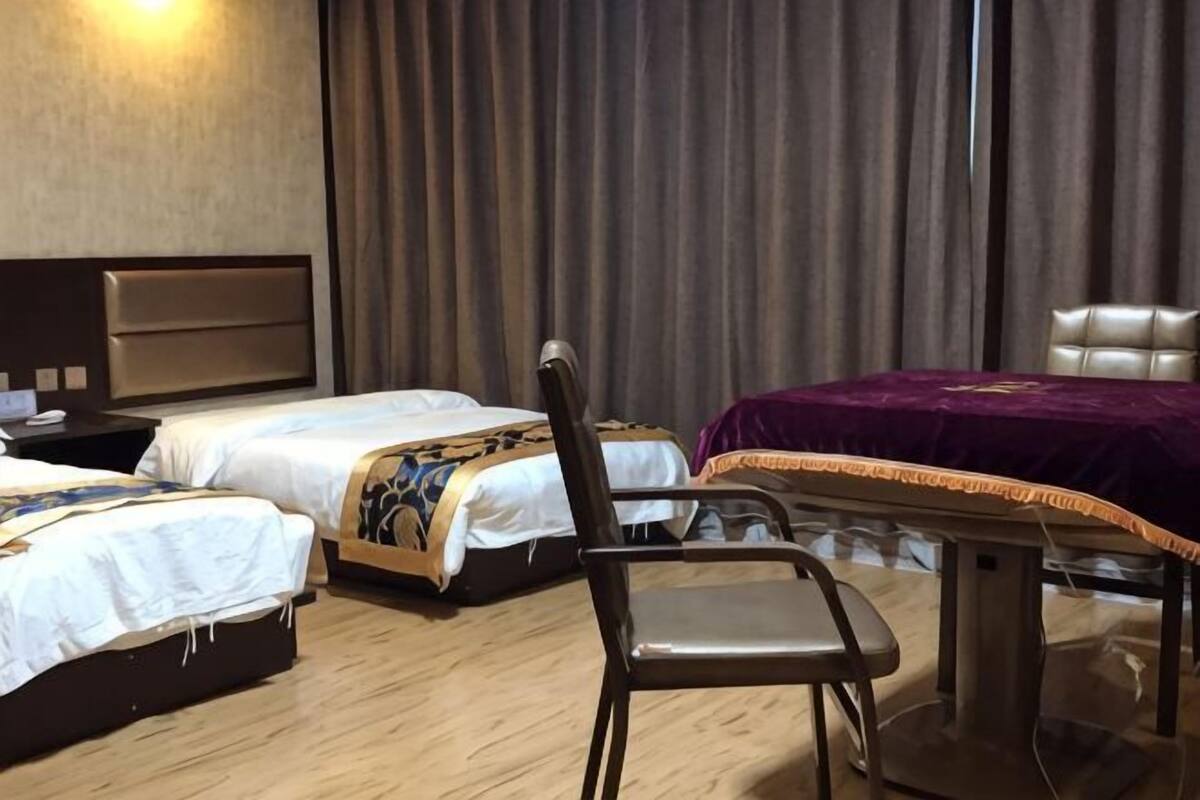 A hotel room with two beds, a dining table, and a chair.