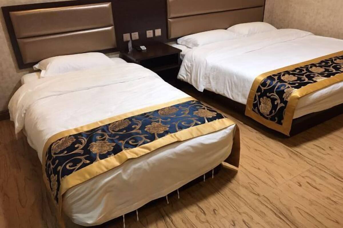 A hotel room with two beds, each with a headboard, a bedside table, and a telephone.