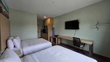 A hotel room with two beds, a desk, a chair, a TV, and a kitchenette.