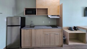 A compact kitchen with a built-in microwave, stainless steel refrigerator, and a sink. - Red Lion Inn & Suites Adairsville (Adairsville)