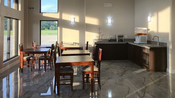 A spacious dining area with a high ceiling, large windows, and a kitchen area with a sink and appliances. - Red Lion Inn & Suites Adairsville (Adairsville)