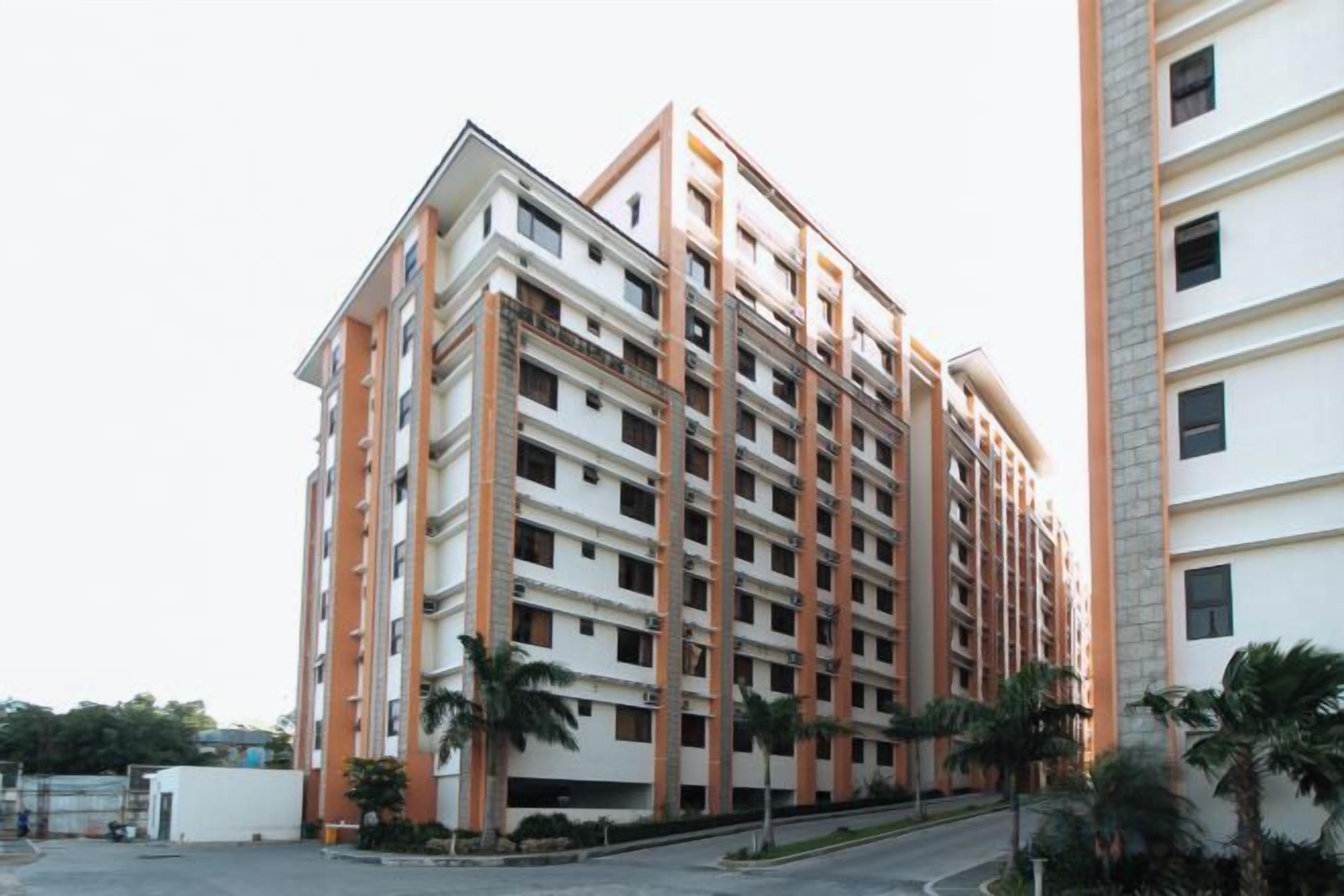 Um edifício residencial de vários andares com fachada uniforme, varandas e entrada com portão.
