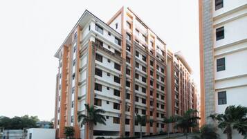 Um edifício residencial de vários andares com fachada uniforme, varandas e entrada com portão.