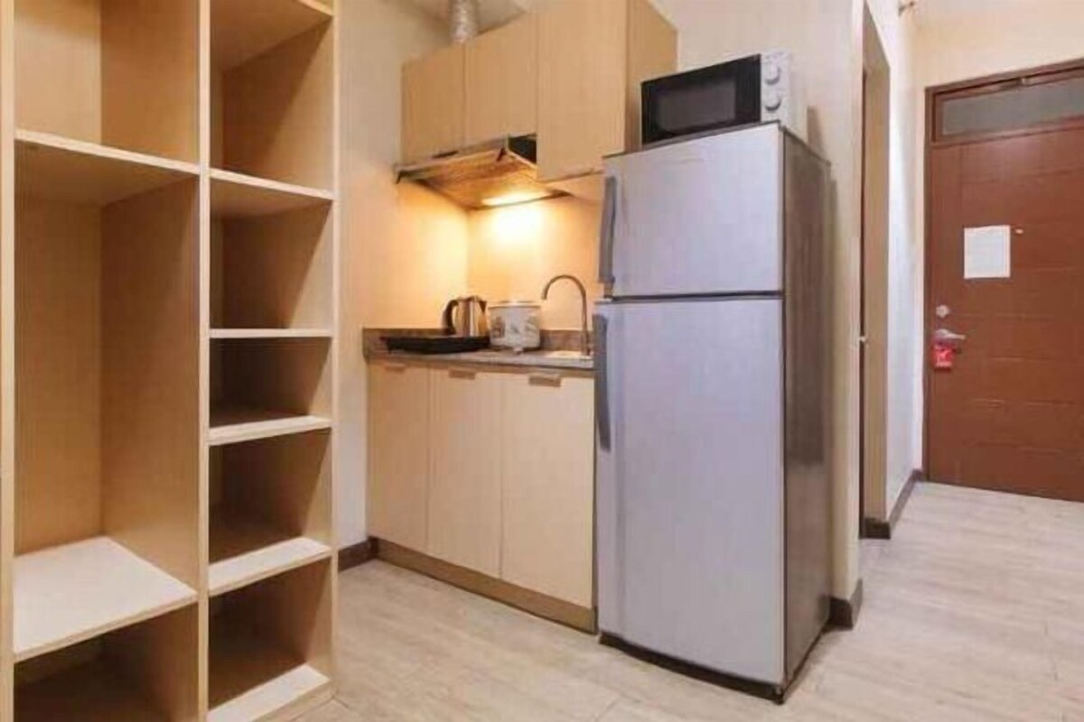 Una cucina compatta con frigorifero, microonde e mobili in legno.