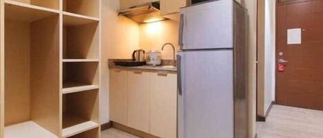 A compact kitchen with a refrigerator, microwave, and wooden cabinets.