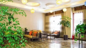 A spacious lobby with a sofa set, chairs, and potted plants.