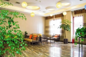 Un vestíbulo de hotel con una zona de estar, una planta grande en maceta y un techo decorativo.
