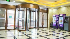 A lobby with a revolving door, a vending machine, and a check-in counter.